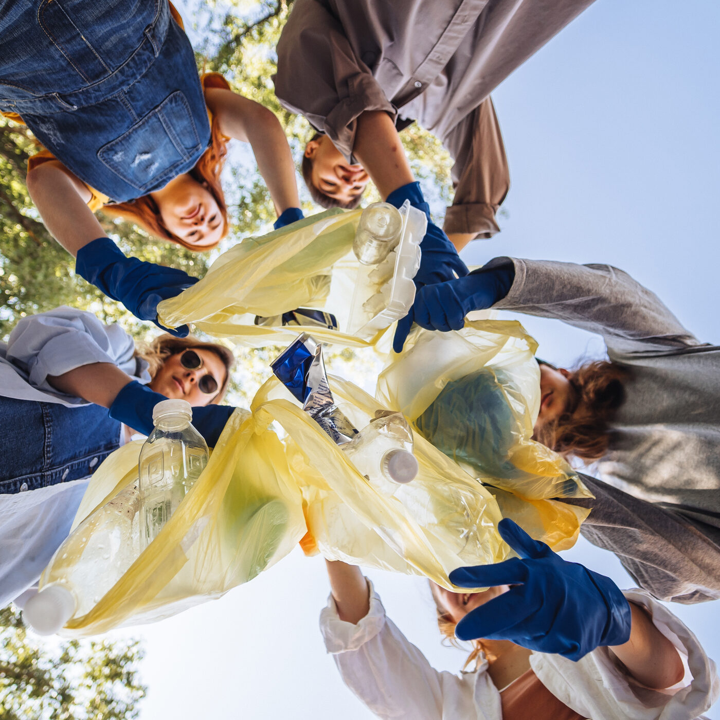 Volunteers standing in a circle, lifting collected rubbish bags together.